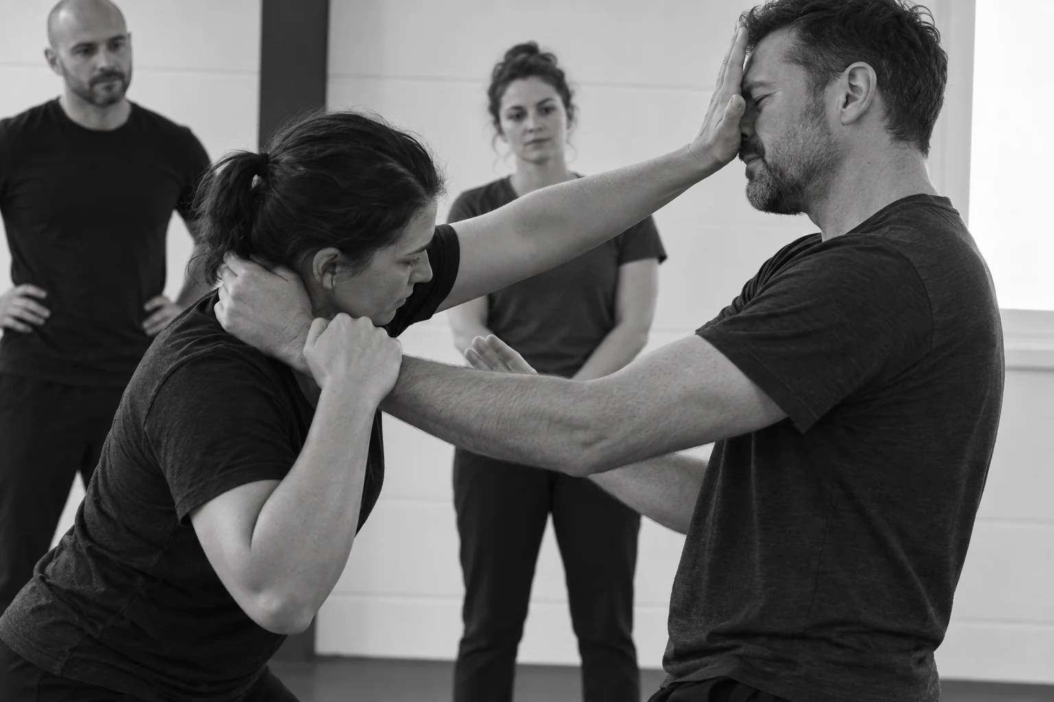Adults practising a controlled personal-safety drill while colleagues observe